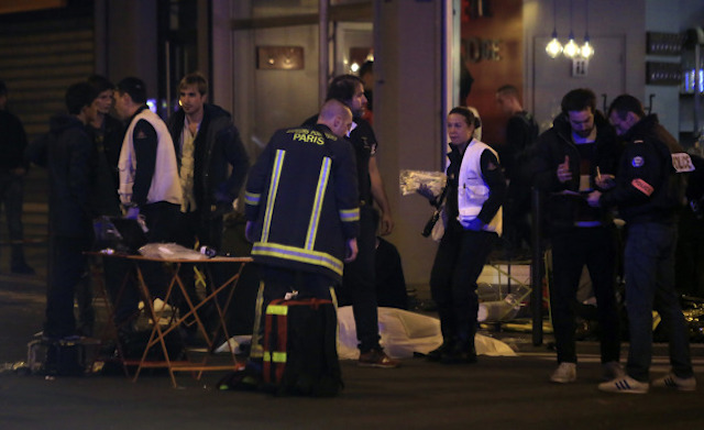 Rescue workers and medics work by victims in a Paris restaurant, Friday, Nov. 13, 2015. Police officials in France on Friday reported a shootout in a Paris restaurant and an explosion in a bar near a Paris stadium. It was unclear if the events were linked. (AP Photo/Thibault Camus)